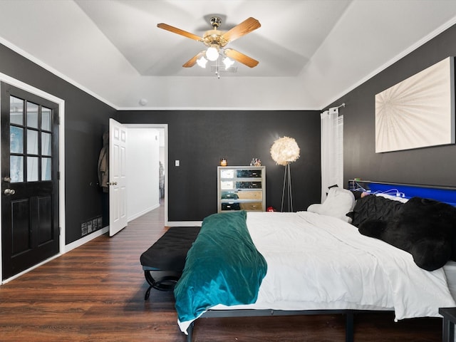 bedroom with a raised ceiling, ceiling fan, crown molding, and dark wood-type flooring