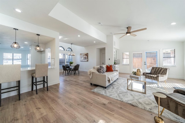 living room with french doors, light hardwood / wood-style floors, ceiling fan, and lofted ceiling