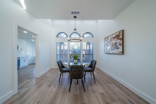 dining room with light hardwood / wood-style floors and an inviting chandelier