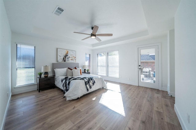 bedroom featuring ceiling fan, light hardwood / wood-style floors, and multiple windows