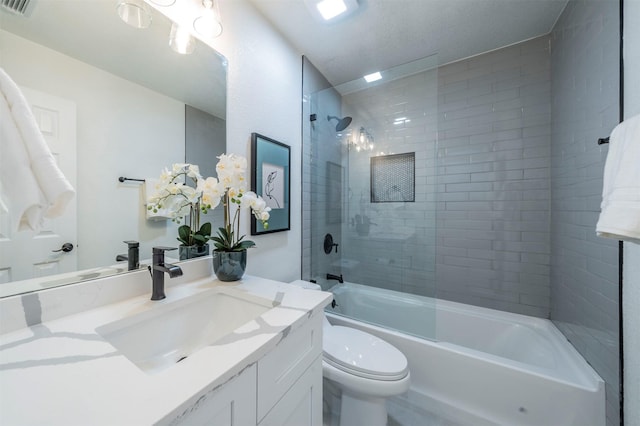 full bathroom featuring toilet, vanity, and tiled shower / bath