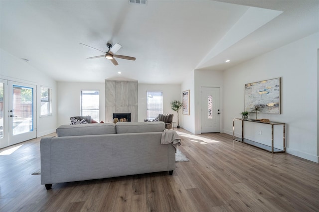 living room with hardwood / wood-style floors, lofted ceiling, a tile fireplace, french doors, and ceiling fan