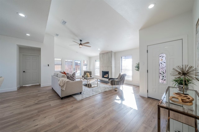 living room featuring ceiling fan, a fireplace, light hardwood / wood-style floors, and lofted ceiling