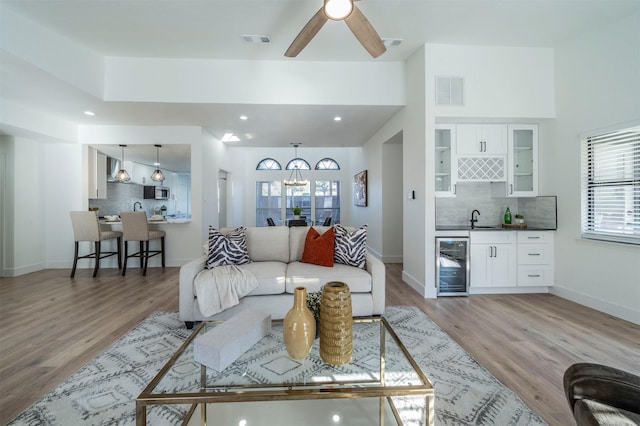 living room with ceiling fan, light wood-type flooring, sink, and wine cooler