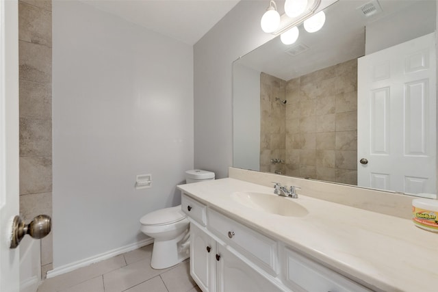 bathroom featuring toilet, a tile shower, vanity, and tile patterned floors