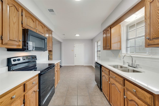 kitchen featuring black appliances, light tile patterned floors, and sink