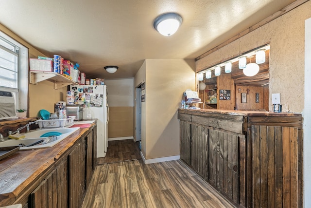 kitchen with dark brown cabinetry, sink, dark wood-type flooring, white fridge, and a textured ceiling