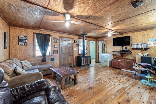 living room with hardwood / wood-style flooring, ceiling fan, and a wood stove