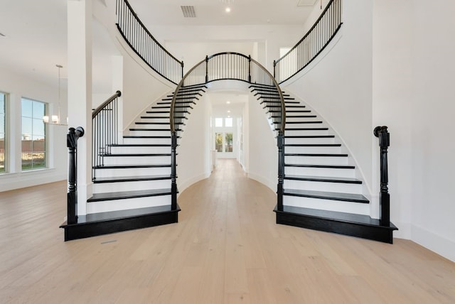 staircase featuring a healthy amount of sunlight, visible vents, arched walkways, and wood finished floors