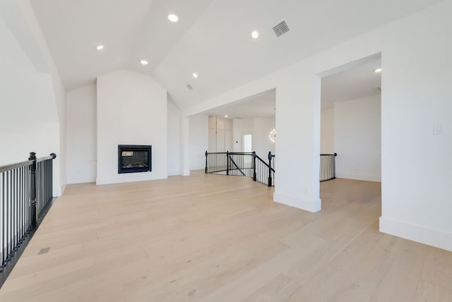 unfurnished living room featuring lofted ceiling and light wood-type flooring