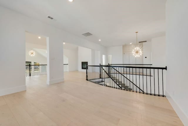 hall with light hardwood / wood-style floors and a chandelier