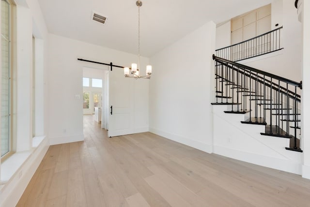 unfurnished dining area featuring wood-type flooring and a barn door