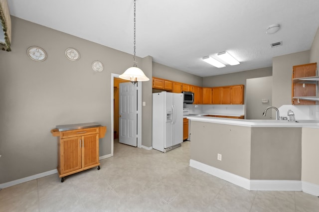 kitchen with kitchen peninsula, decorative light fixtures, white fridge with ice dispenser, and sink