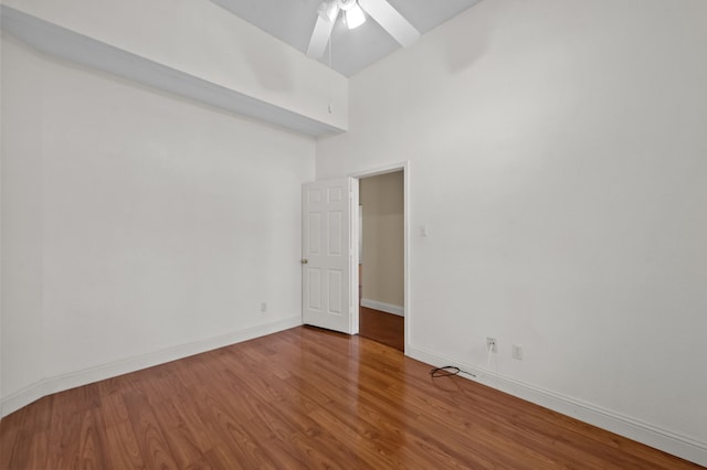 unfurnished room featuring ceiling fan, a high ceiling, and hardwood / wood-style flooring