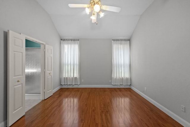 empty room with ceiling fan, lofted ceiling, and wood-type flooring