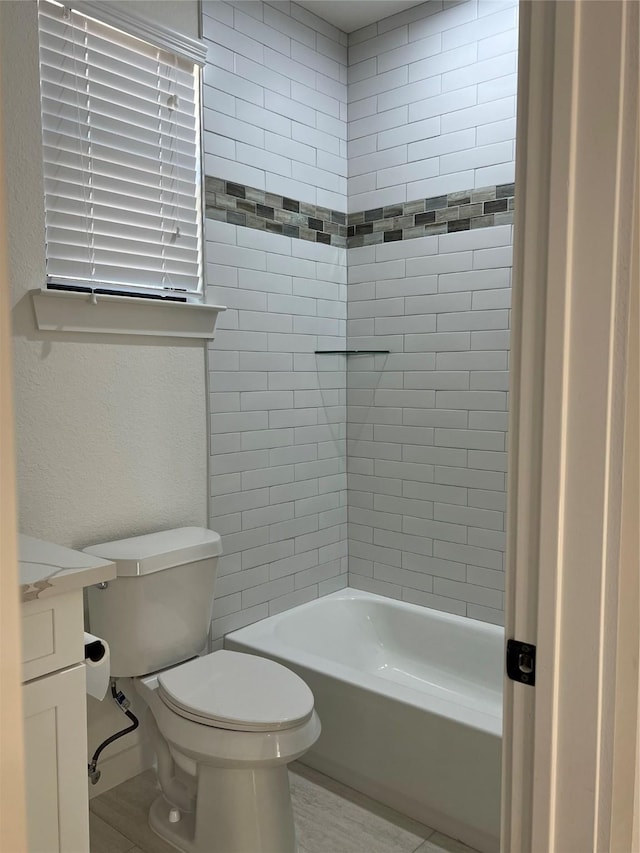 full bathroom featuring vanity, tiled shower / bath combo, and toilet