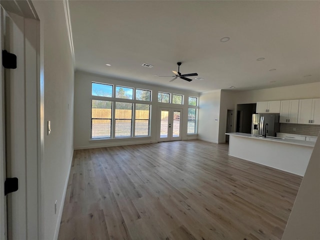 unfurnished living room with ceiling fan and light wood-type flooring