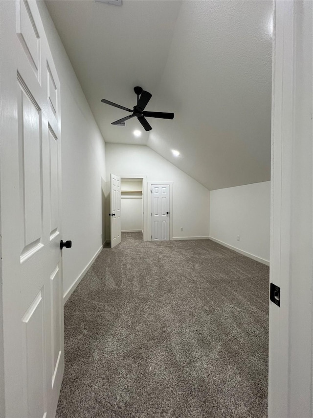 bonus room with a textured ceiling, ceiling fan, dark carpet, and lofted ceiling