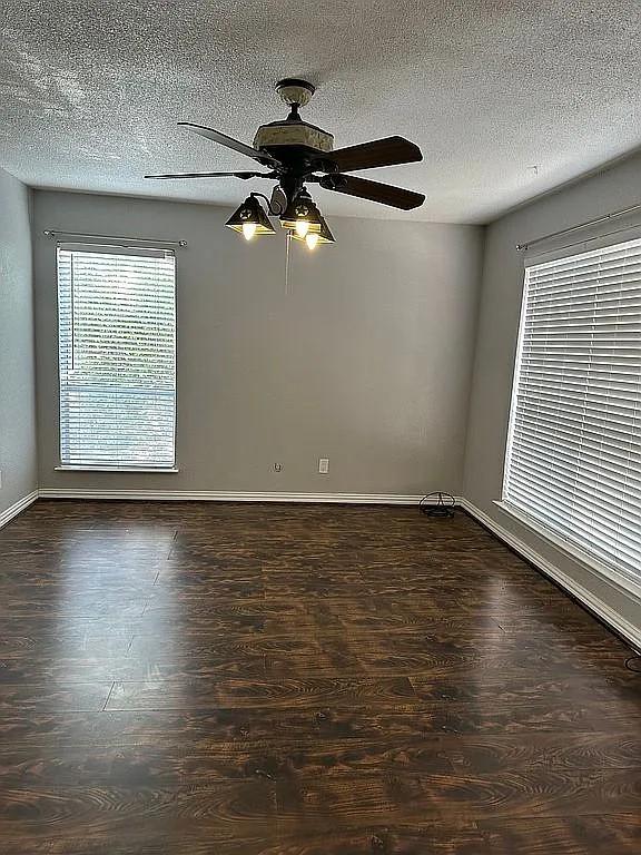 spare room featuring ceiling fan, dark wood-type flooring, and a textured ceiling