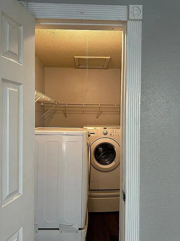 laundry room featuring independent washer and dryer, a textured ceiling, and wood-type flooring