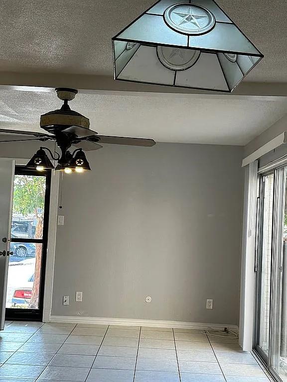 unfurnished dining area featuring plenty of natural light, ceiling fan, light tile patterned floors, and a textured ceiling