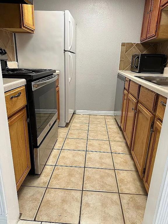 kitchen featuring tasteful backsplash, light tile patterned floors, and appliances with stainless steel finishes