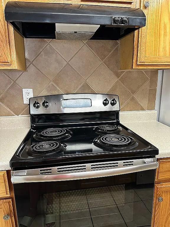 kitchen featuring decorative backsplash, tile patterned flooring, stainless steel range with electric cooktop, and exhaust hood