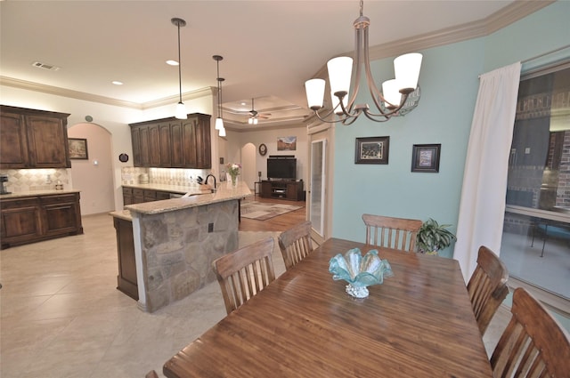 tiled dining space with crown molding, sink, and ceiling fan with notable chandelier