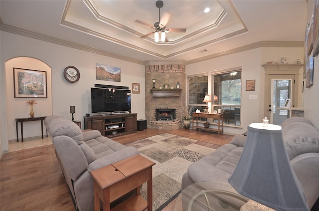 living room featuring ceiling fan, wood-type flooring, crown molding, and a tray ceiling