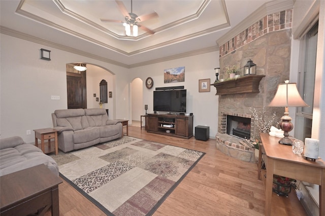 living room with ceiling fan, ornamental molding, light hardwood / wood-style flooring, and a tray ceiling