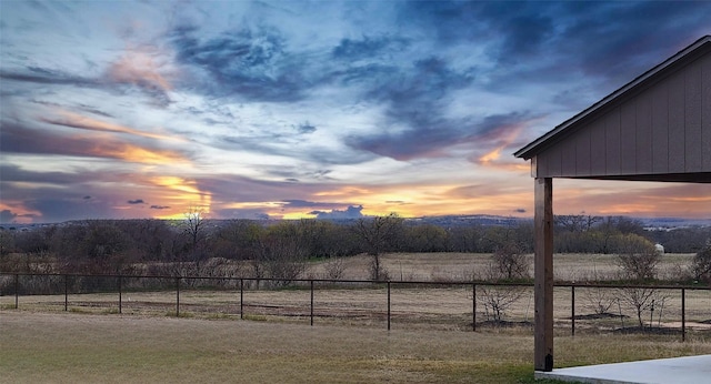 yard at dusk featuring a rural view