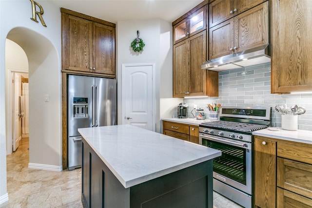 3308 Estacado Dr, Denton, TX 76210 - kitchen featuring stainless steel appliances, under cabinet range hood, backsplash, arched walkways, and a center island