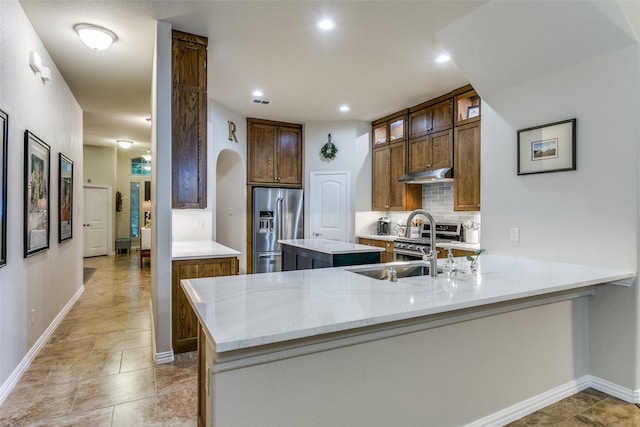 3308 Estacado Dr, Denton, TX 76210 - kitchen featuring a center island, stainless steel fridge, arched walkways, under cabinet range hood, and tasteful backsplash