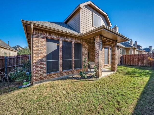 rear view of property featuring a patio and a lawn