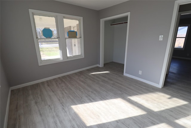 unfurnished bedroom featuring wood finished floors, baseboards, and a closet