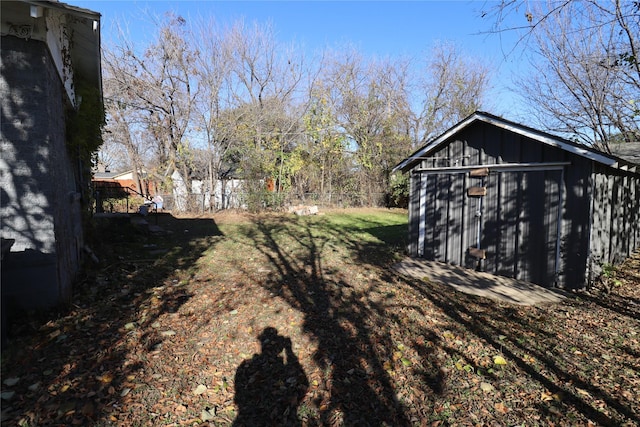 view of yard featuring an outbuilding, a storage shed, and fence