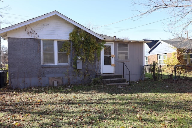 bungalow-style home with entry steps, a front lawn, and fence