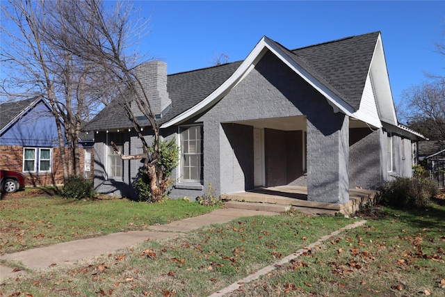 bungalow-style home with a front lawn, stucco siding, a chimney, and a shingled roof