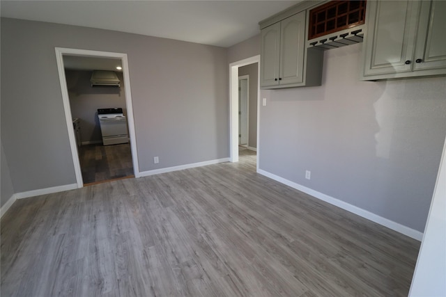 interior space with white range with electric cooktop, light wood-style flooring, ventilation hood, and baseboards