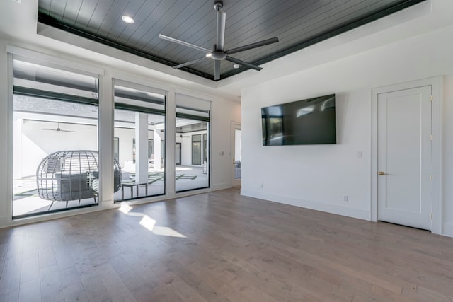 unfurnished room with ceiling fan, a tray ceiling, and hardwood / wood-style floors