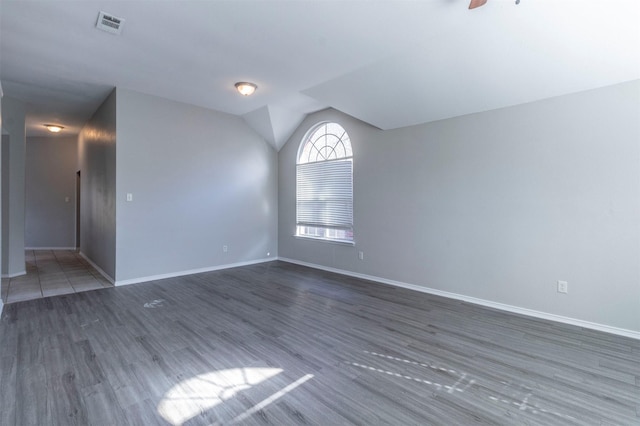 spare room featuring dark wood-type flooring and vaulted ceiling