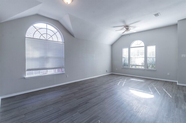 spare room featuring vaulted ceiling, plenty of natural light, dark wood-type flooring, and ceiling fan