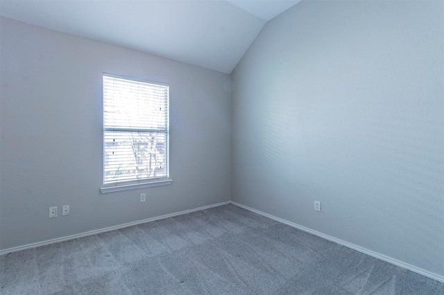 spare room with vaulted ceiling and dark colored carpet