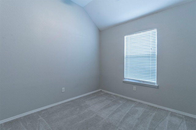 carpeted spare room featuring vaulted ceiling