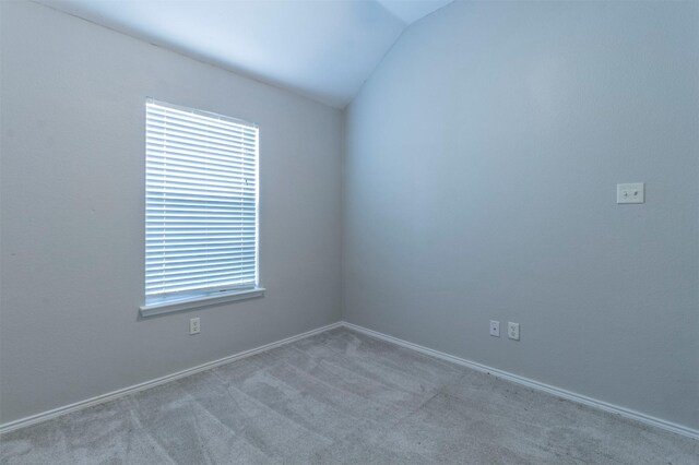 empty room featuring vaulted ceiling, light colored carpet, and a healthy amount of sunlight