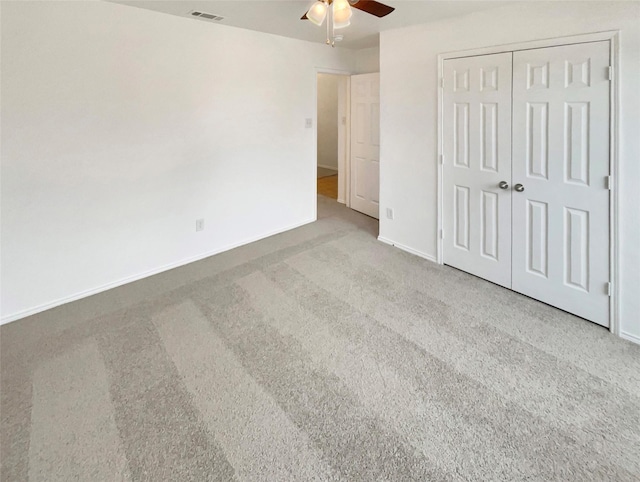 unfurnished bedroom featuring light colored carpet, ceiling fan, and a closet