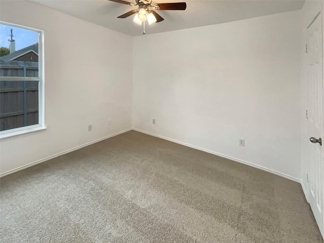 empty room featuring ceiling fan and dark colored carpet