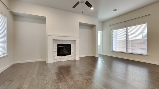 unfurnished living room with ceiling fan, plenty of natural light, dark hardwood / wood-style floors, and a fireplace