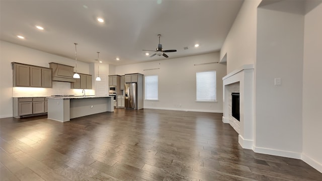 unfurnished living room with dark wood-type flooring, ceiling fan, and sink