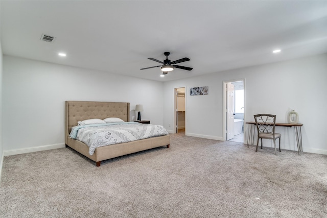 carpeted bedroom featuring ceiling fan and a walk in closet